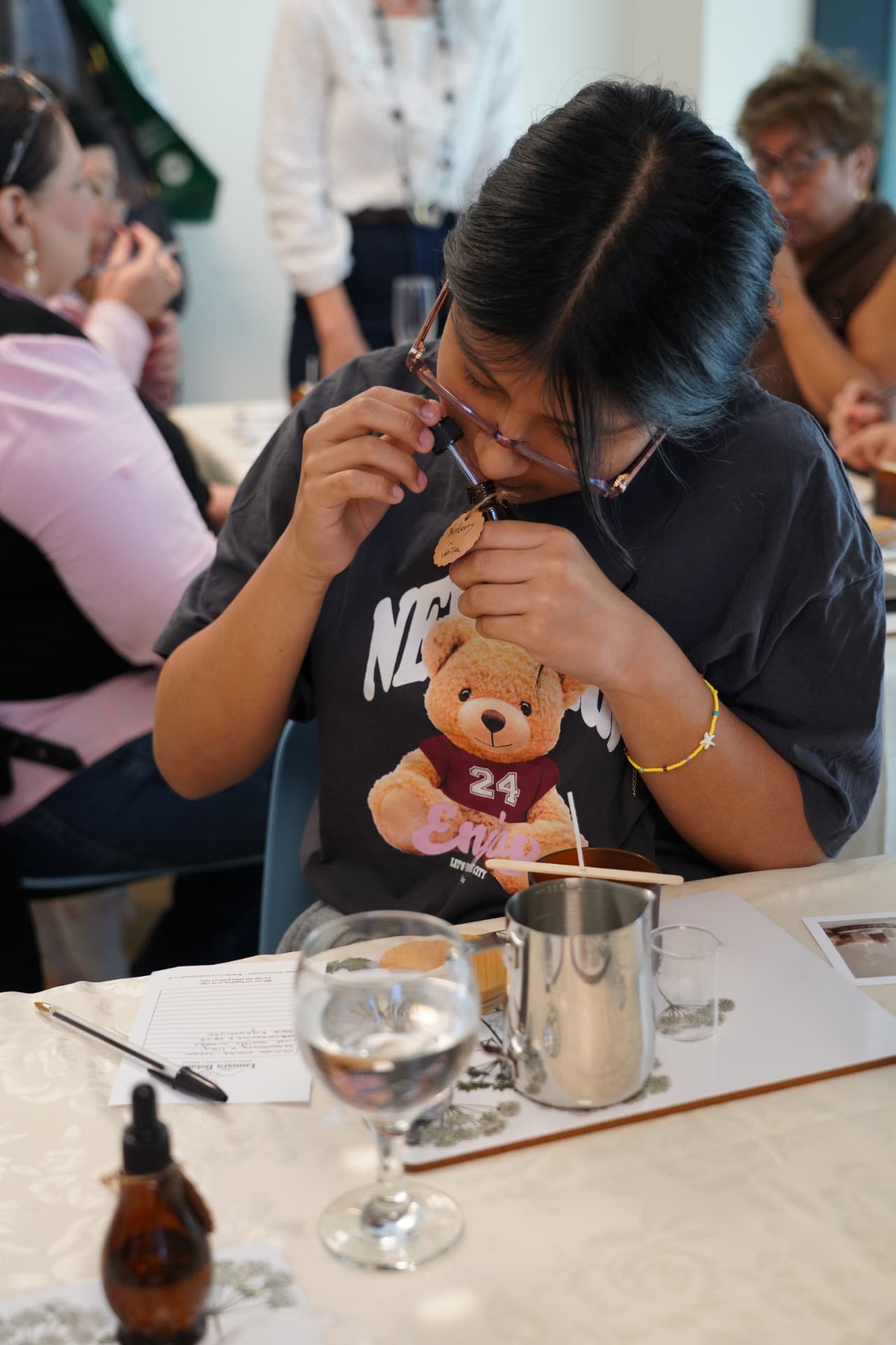 A workshop guest smelling an essential oil from an amber dropper bottle
