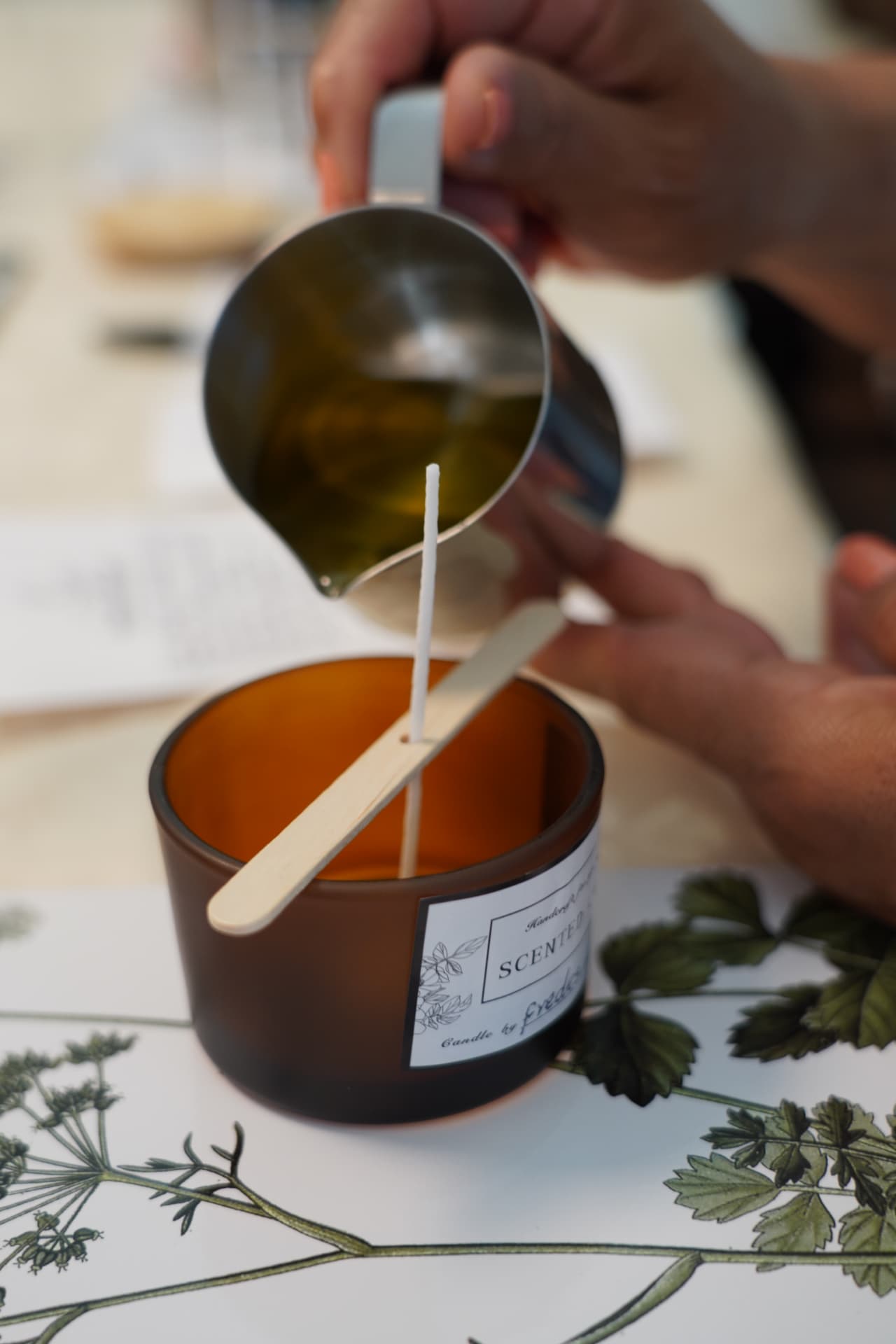 Warm soy wax being poured into an amber candle vessel at a Lumara Botanic workshop