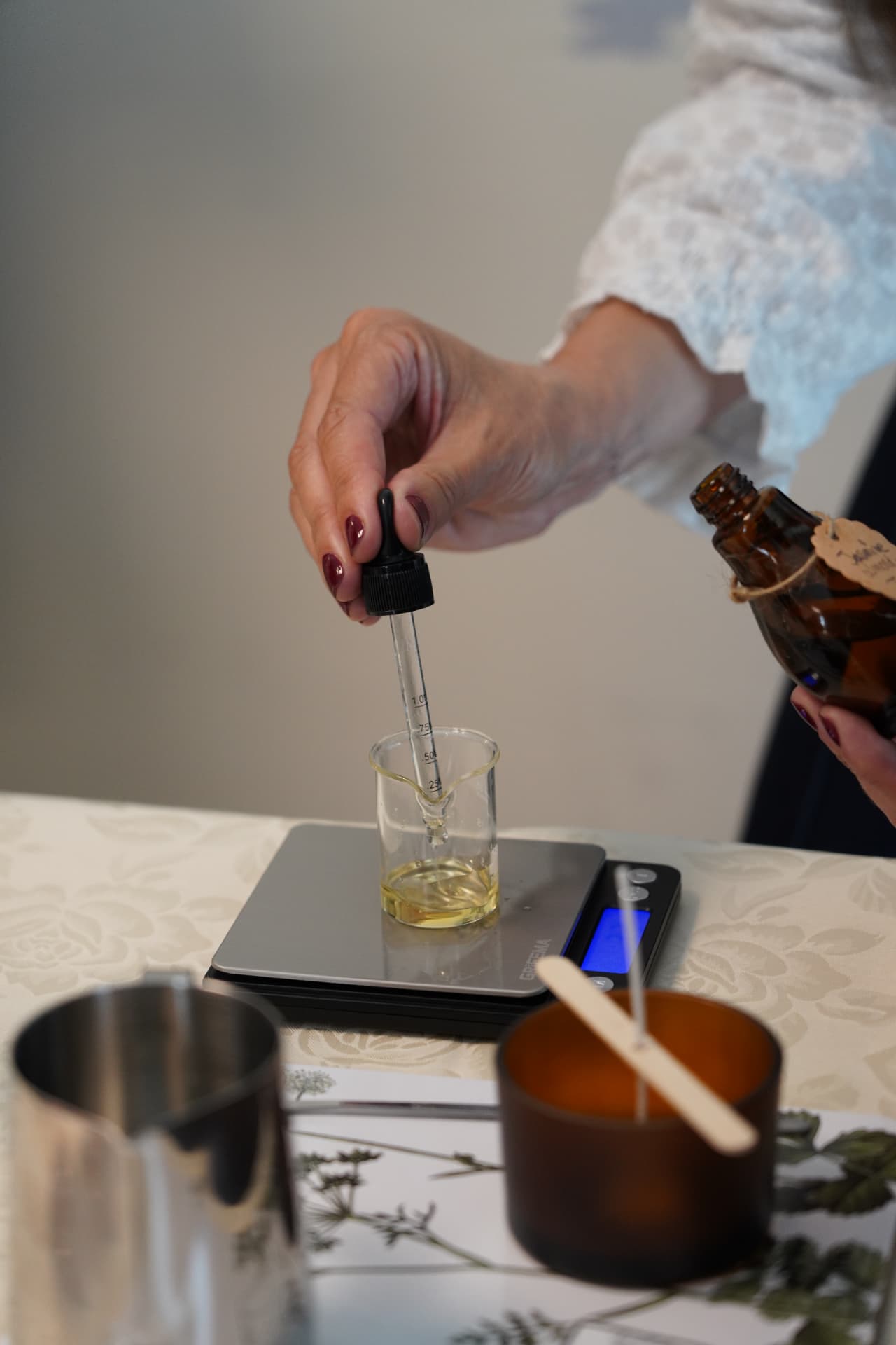 Essential oil being measured drop by drop into a glass beaker on a scale