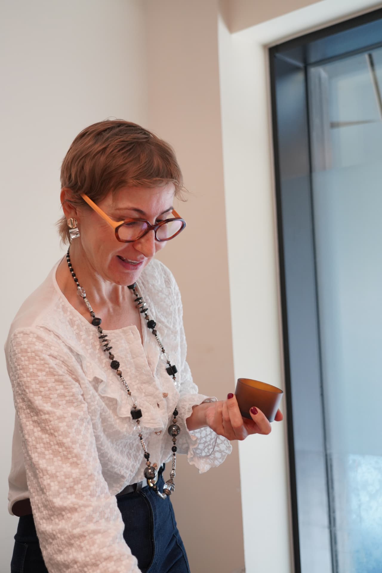 Raquel Misis holding an amber candle vessel by a window